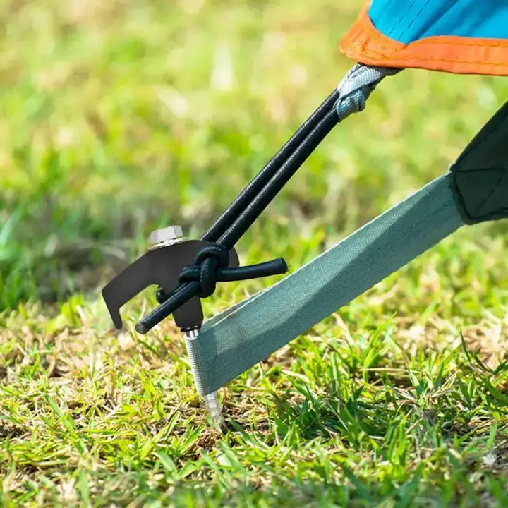 Tent secured with sturdy metal spiral screw stake on grassy ground.