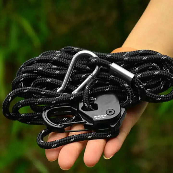 Hand holding a black rope tensioner with carabiner, ideal for camping tents, featuring a quick release system and lightweight design.