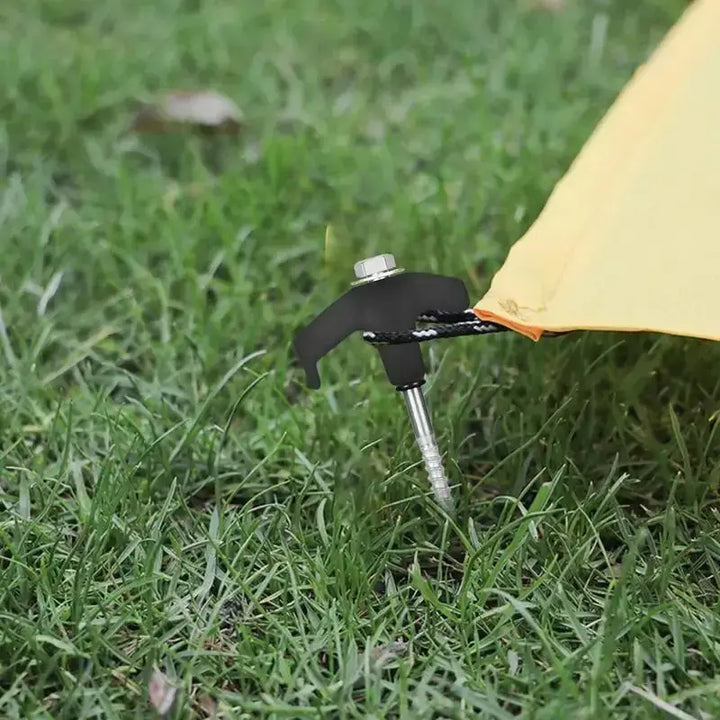 Sturdy metal tent stake with spiral screw design securing a yellow tent on grassy ground.