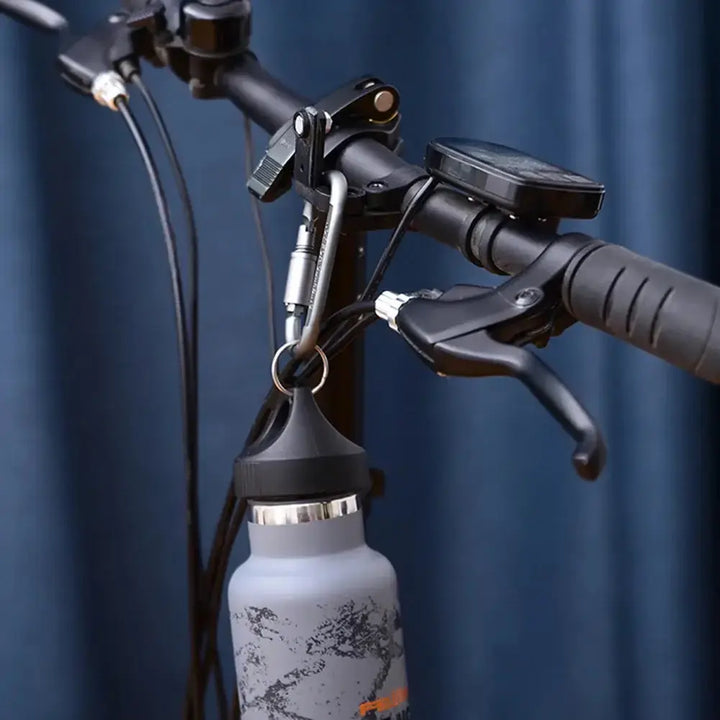 Bicycle handlebar with a metal carabiner holding a water bottle, showcasing multifunctional carabiner use for outdoor activities.