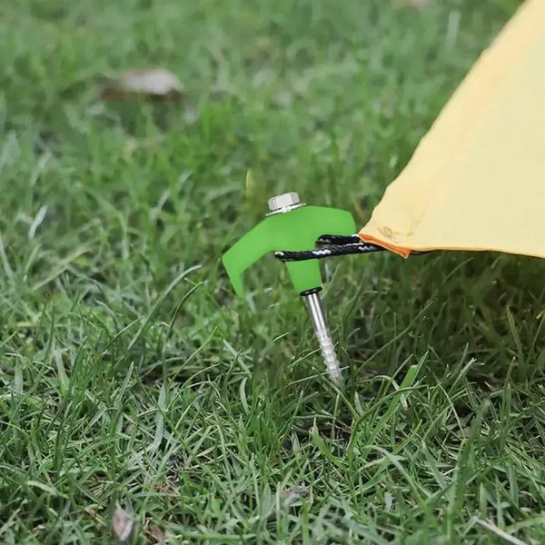 Screw-in metal tent stake securing yellow tent on grassy ground for camping trips.