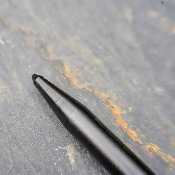 Close-up of a steel tent peg tip on a textured surface, ideal for securing tents and tarps in outdoor camping setups.